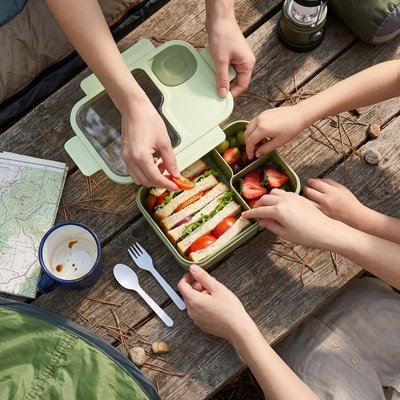 Lunch box enfant verte ouverte sur table pique-nique