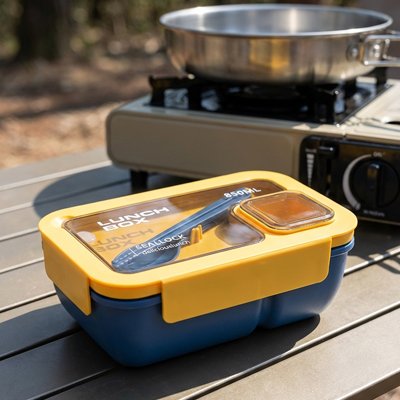 Boite a lunch jaune près réchaud sur table camping