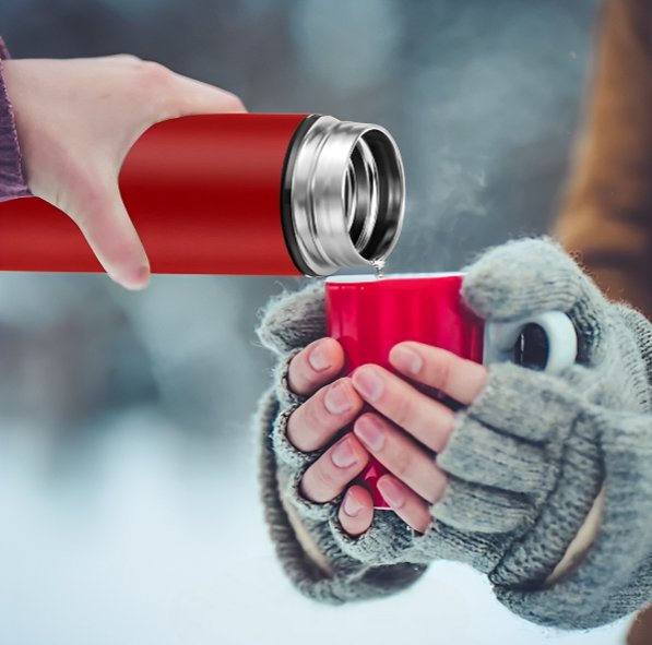 Bouteille isotherme rouge verse liquide dans tasse en hiver
