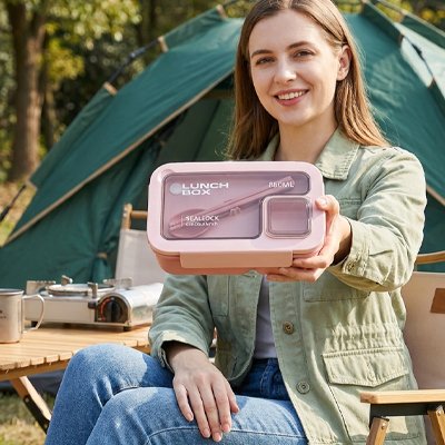 Femme assise avec boite a lunch rose en camping