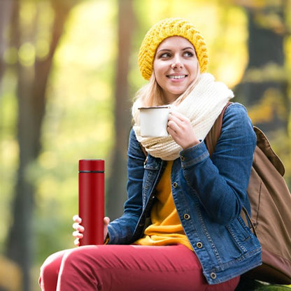 Femme assise avec bouteille isotherme rouge en forêt
