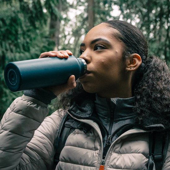 Femme boit avec gourde isotherme plein air