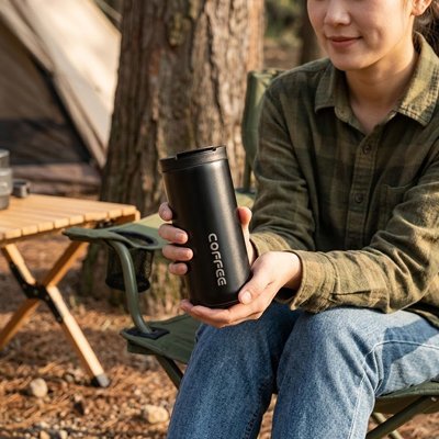 Femme camping tient tasse isotherme noire
