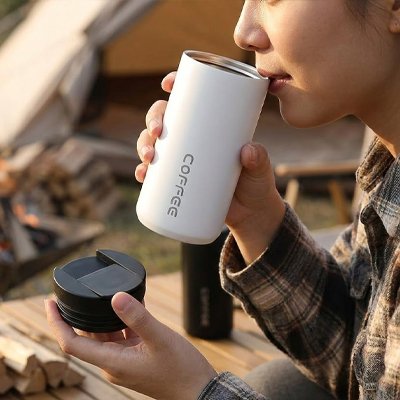 Femme dehors boit avec tasse isotherme blanche