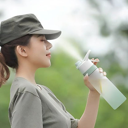 Femme rafraîchit visage avec vaporisateur gourde blanche et verte 