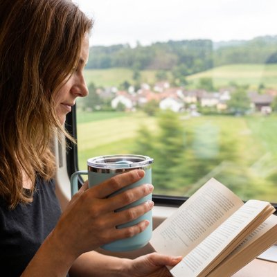 Femme tient tasse isotherme bleue pâle voyqge train