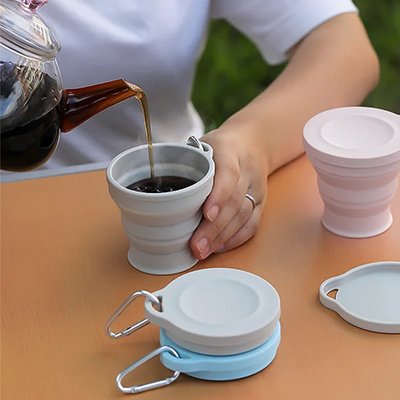 Femme verse thé dans gobelet pliable gris clair