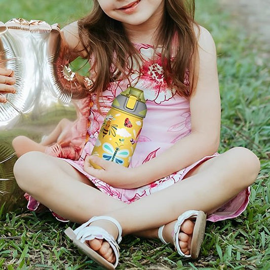 Fillette assise gazon avec gourde enfant jaune