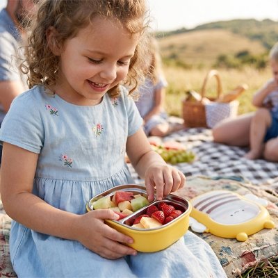 Fillette mange avec lunch box enfant pique-nique