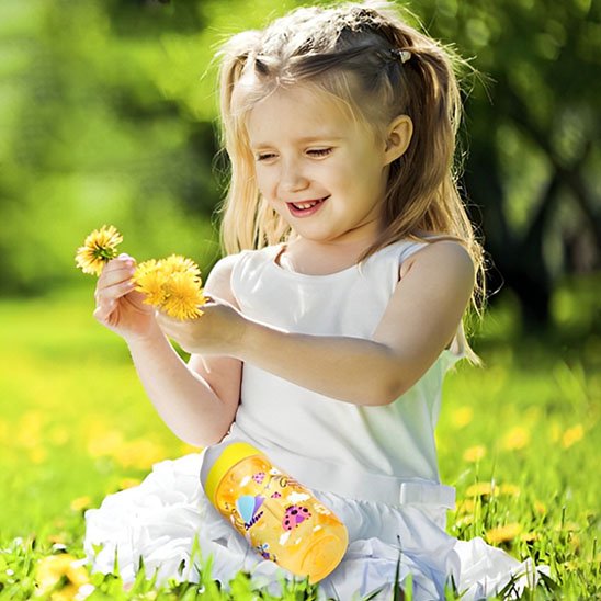 Fillette souriante avec gourde enfant jaune en plein air