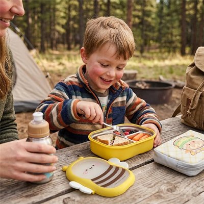 Garçonnet déjeune avec lunch box enfant camping