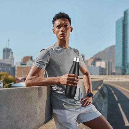 Homme au repos après jogging avec bouteille isotherme noire