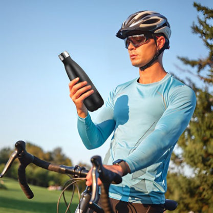 Homme en vélo arrêté pour boire avec bouteille isotherme noire