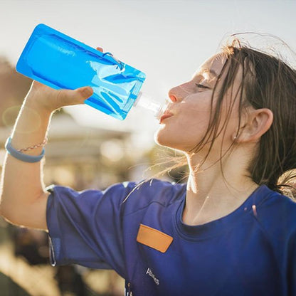 Jeune fille boit gourde plastique bleue plein air