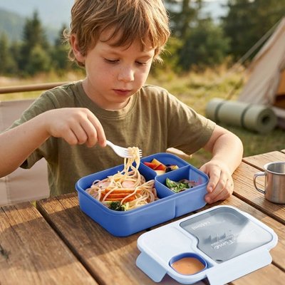 Jeune garçon mange dans lunch box enfant bleue plein air