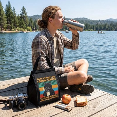 Jeune homme déjeune quai lac avec sac isotherme noir 