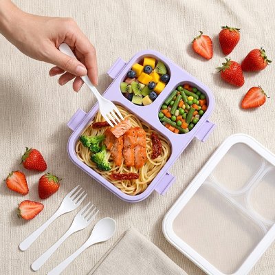 Lunch box violette ouverte sur table avec couverts