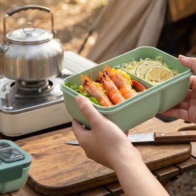 Personne camping tient boite a lunch verte remplie nourriture